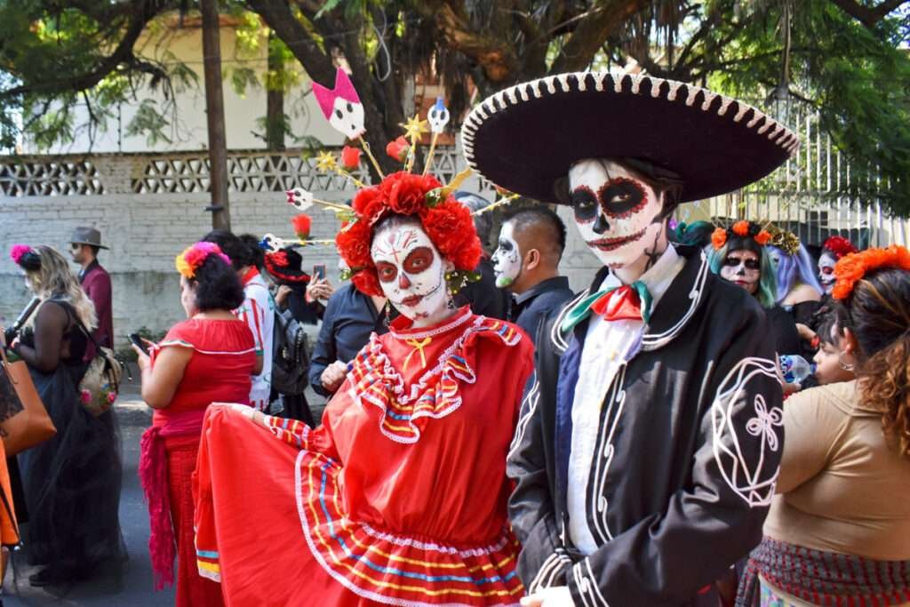 Tag der Toten – Menschen in traditionellen Kostümen und Gesichtern bemalt als Calaveras auf einer Parade in Mexiko