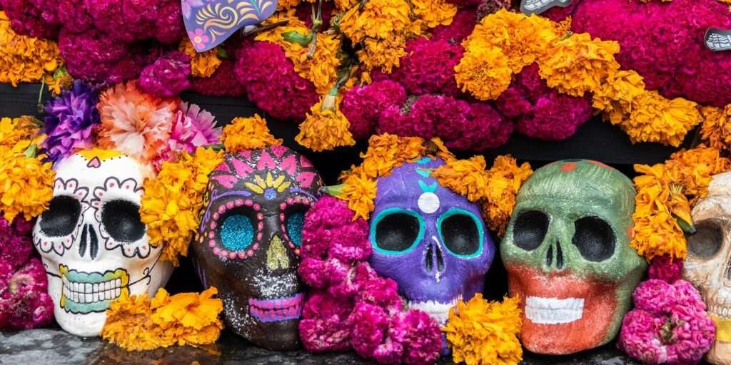 Tag der Toten – farbenfrohe Totenköpfe und traditionelle Blumen auf einer Ofrenda in Mexiko
