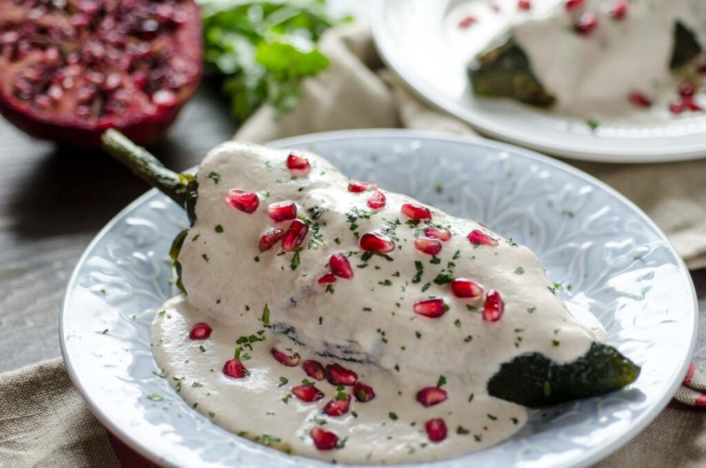 Chiles en Nogada angerichtet auf traditionellem Teller mit Granatapfel und Petersilie – Mexidom in Mexiko