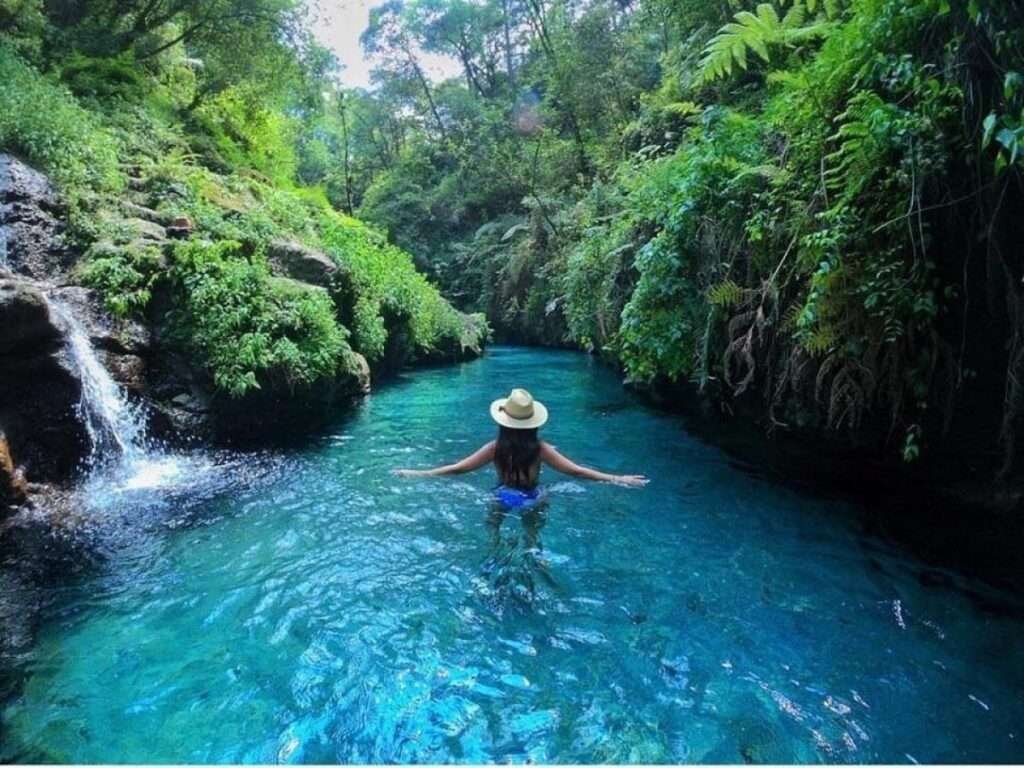 Frau schwimmt im türkisblauen Fluss Pancho Poza in Veracruz – Symbolbild für Grundstückspreise in Mexiko
