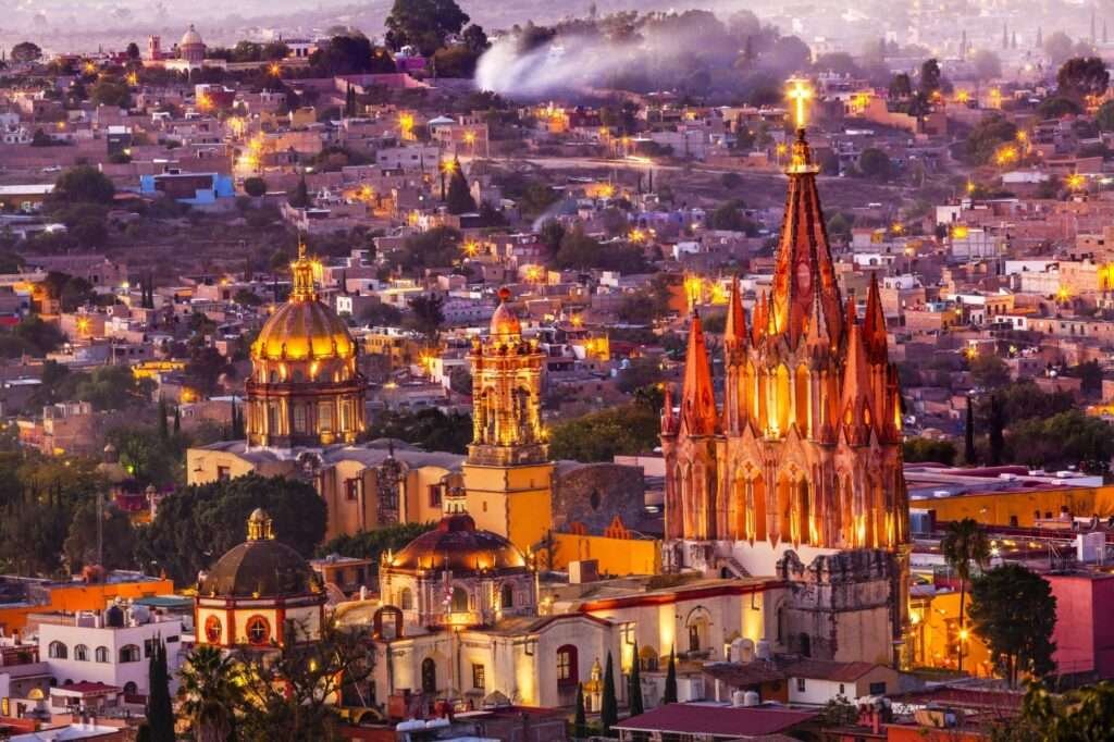 Blick über die Stadt bei Dämmerung mit leuchtender Parroquia – das typische Leben in San Miguel de Allende.