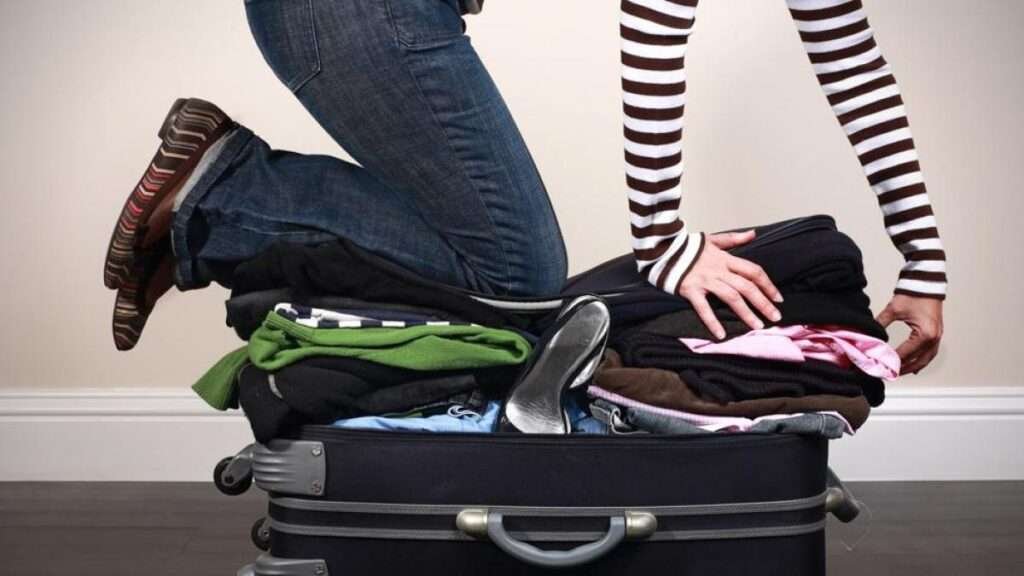Person sitzt auf überfülltem Koffer – falsche Packliste für Mexiko