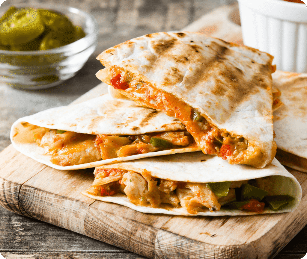 Quesadillas aus Mexiko mit Hähnchen und Paprika auf Holzbrett