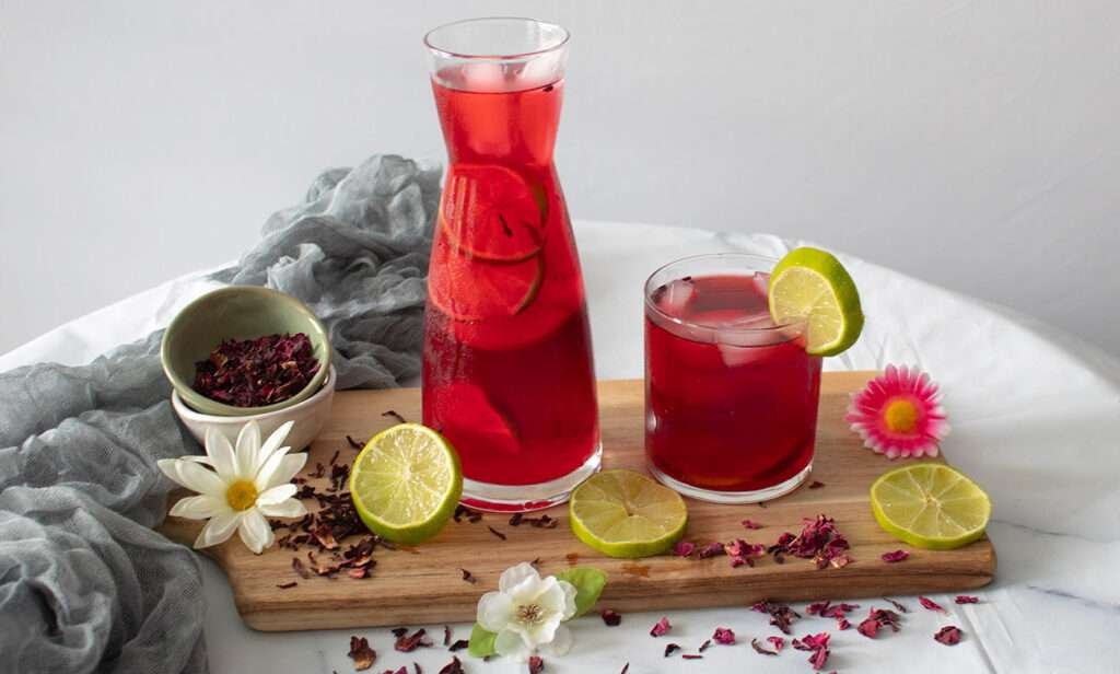 Karaffe und Glas mit Agua de Jamaica Hibiscusblüten-Tee, serviert mit Limette