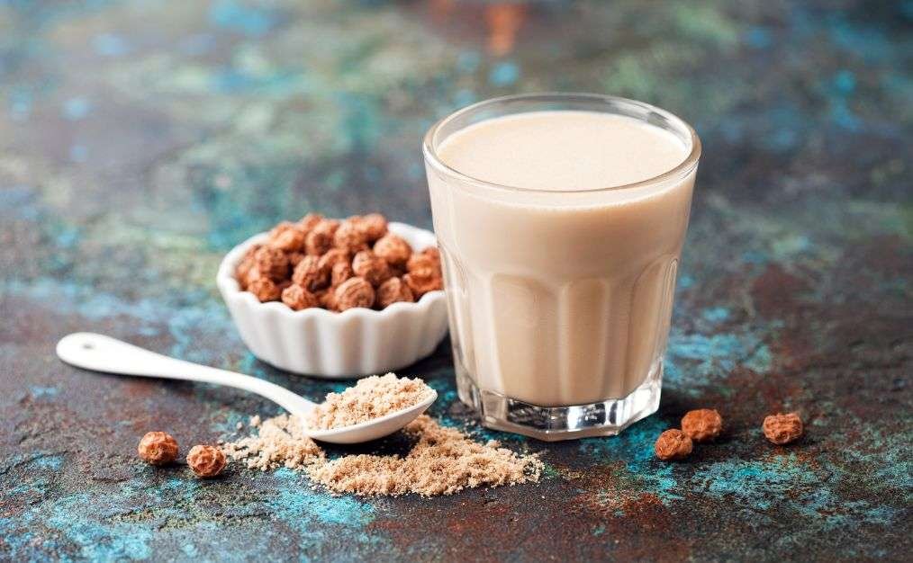 Traditionelle Horchata aus Erdmandeln im Glas, daneben gemahlene Chufas – Ursprung des beliebten Getränks

