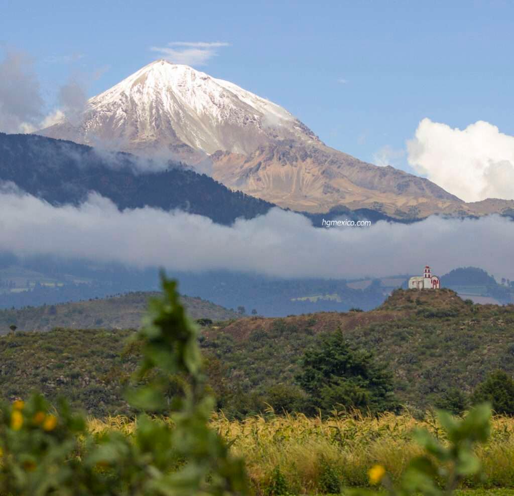 Der Pico de Orizaba, der höchste der drei höchsten Berge Mexikos, ragt über eine kleine Kapelle und ein grünes Tal hinaus