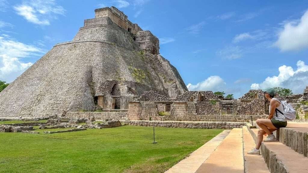 Frau sitzt vor der Pyramide des Zauberers in den Ruinen von Uxmal, Yucatán