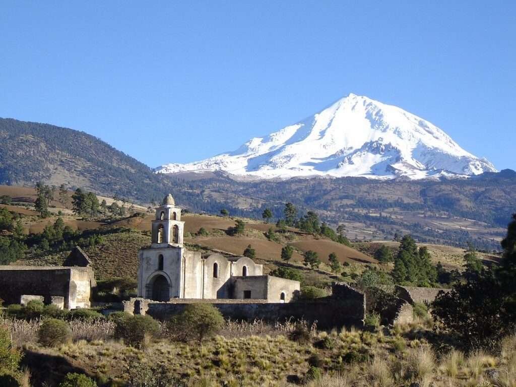 Blick auf den schneebedeckten Pico de Orizaba mit historischer Kapelle im Vordergrund