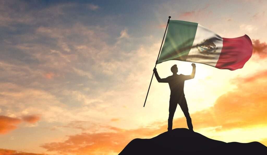 Silhouette eines Mannes mit mexikanischer Flagge als Symbol für Mexikanischer Nationalstolz bei Sonnenuntergang