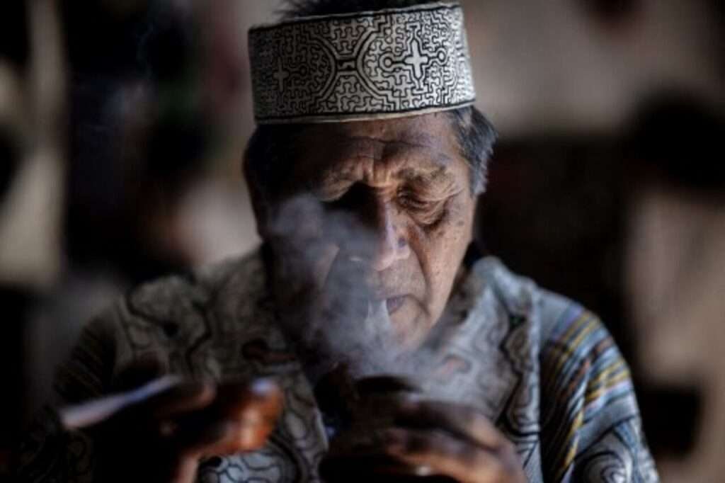 Curandero aus Mexiko bläst Rauch bei spirituellem Reinigungsritual - Schamanismus in Mexiko