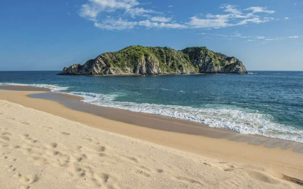 Unberührter Sandstrand mit Insel vor der Küste von Oaxaca Mexiko