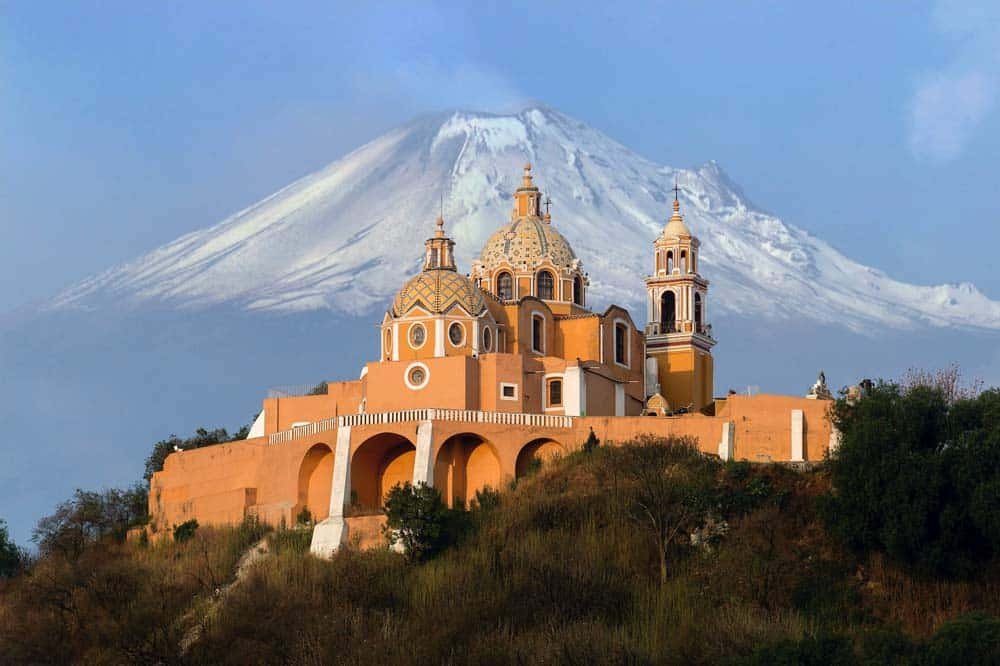 Kirche von Cholula mit dem Vulkan Popocatépetl – perfektes Beispiel, warum Mexiko hat das beste Klima